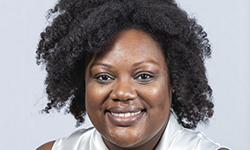 Smiling person with curly hair.