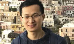 Man smiling in front of colorful buildings.