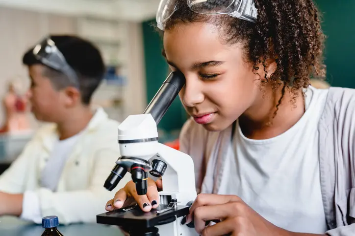 Girl using microscope in science class.