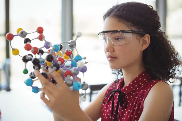 Woman examining molecular model with safety glasses.