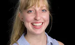 Smiling person with blonde hair and bangs.