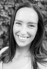 Smiling person with long hair, grayscale photo.