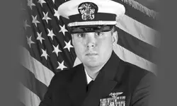 Navy officer in uniform with American flag.