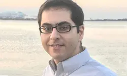 Man smiling by the waterfront at sunset.