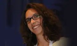 Smiling woman with glasses and curly hair.