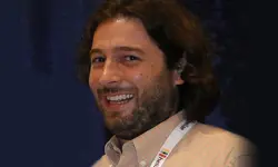 Smiling person with a conference badge.