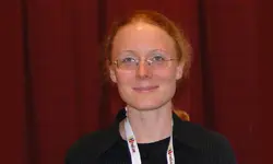 Smiling person with glasses and lanyard.