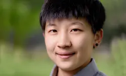 Smiling person with short hair, green background.