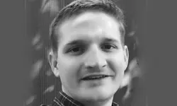 Man smiling in black and white portrait.