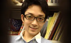 Smiling person with glasses in a library.