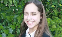 Smiling girl in front of green leaves.