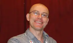 Smiling person wearing glasses and plaid shirt.