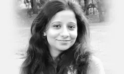 Smiling woman in outdoor black-and-white portrait.