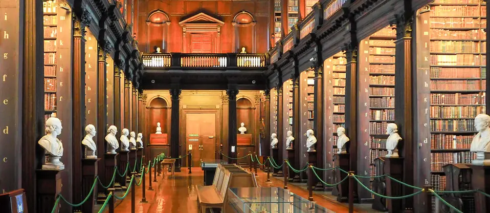 Historic library with books and marble busts.