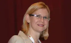 Smiling woman with glasses and blonde hair.