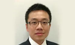 Man wearing glasses and suit, neutral background.