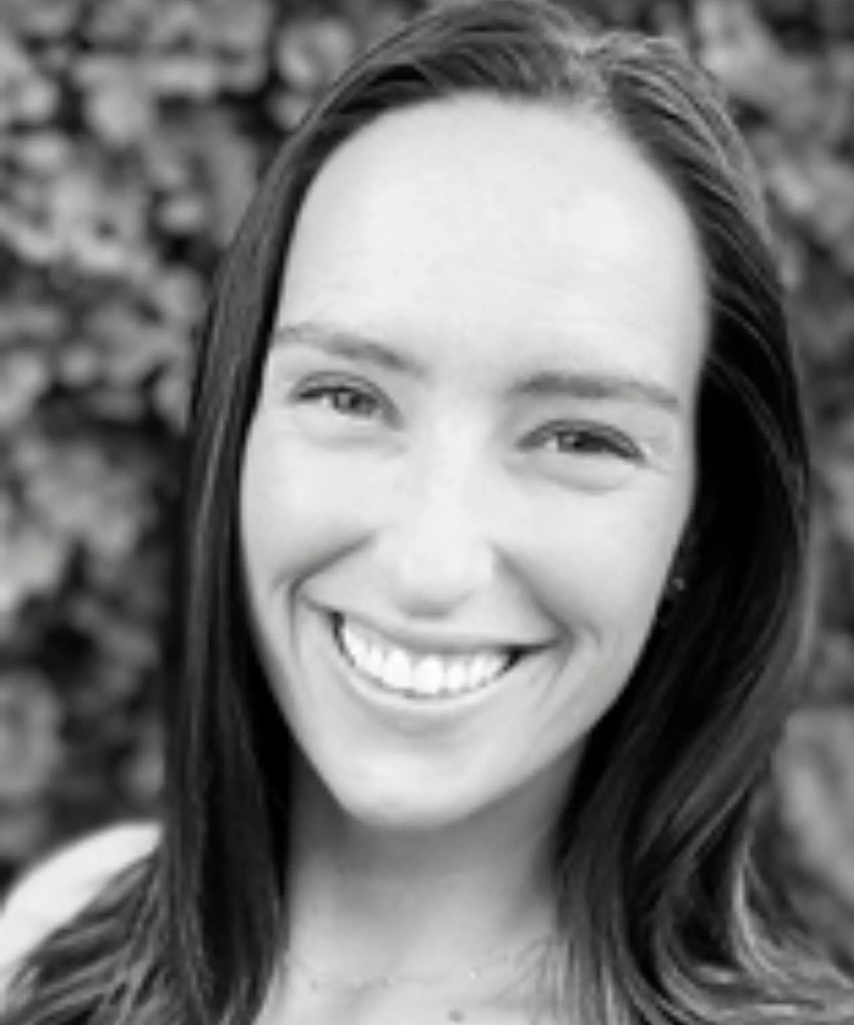 Close-up black and white portrait of a smiling woman.