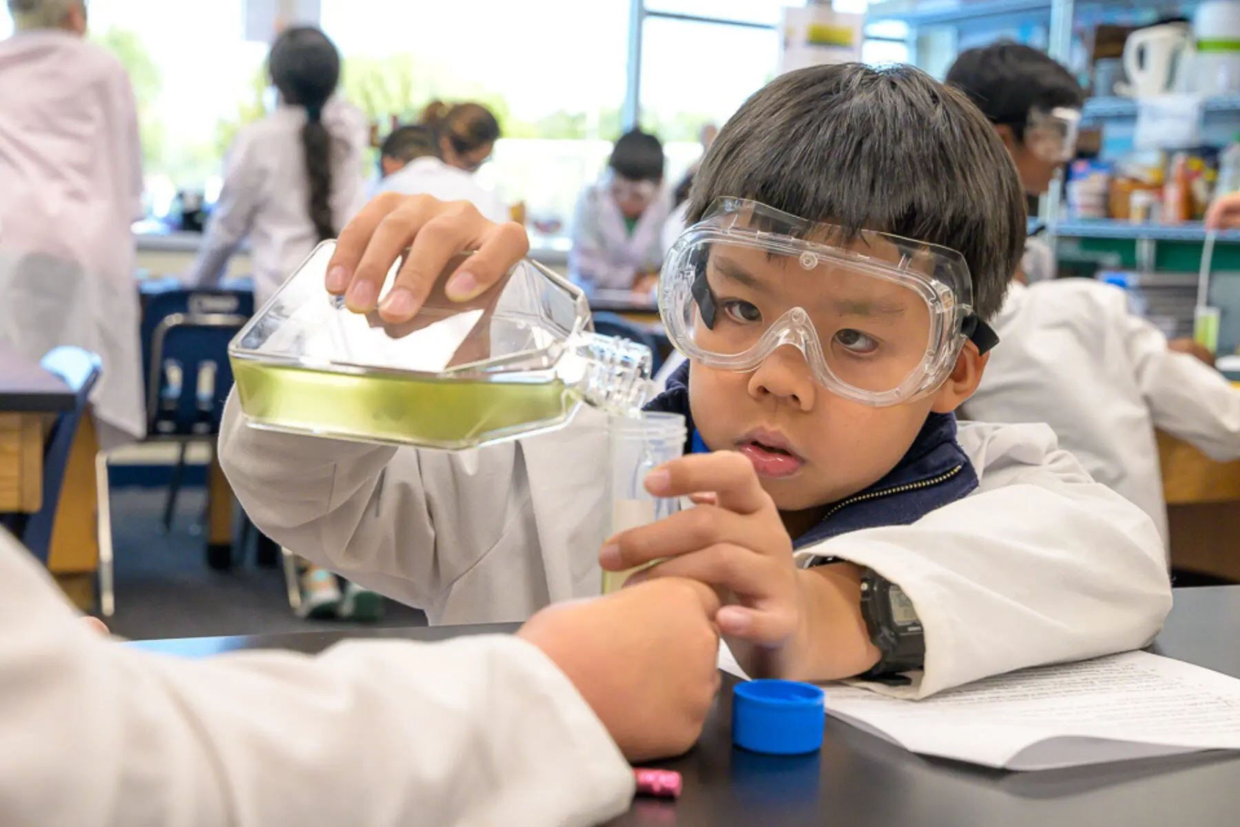 Young student conducting a science experiment wearing safety goggles.