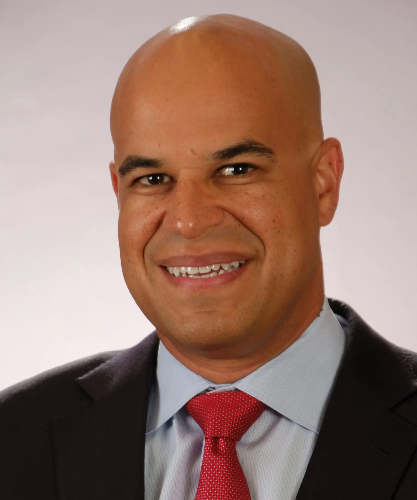 Professional man in suit and red tie smiling at the camera.