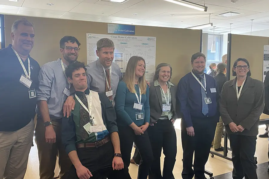 Group of six professionals posing together at a conference or event.