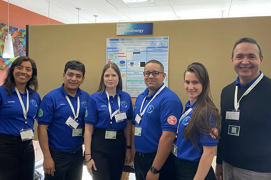 Four individuals wearing blue shirts with badges, standing indoors.