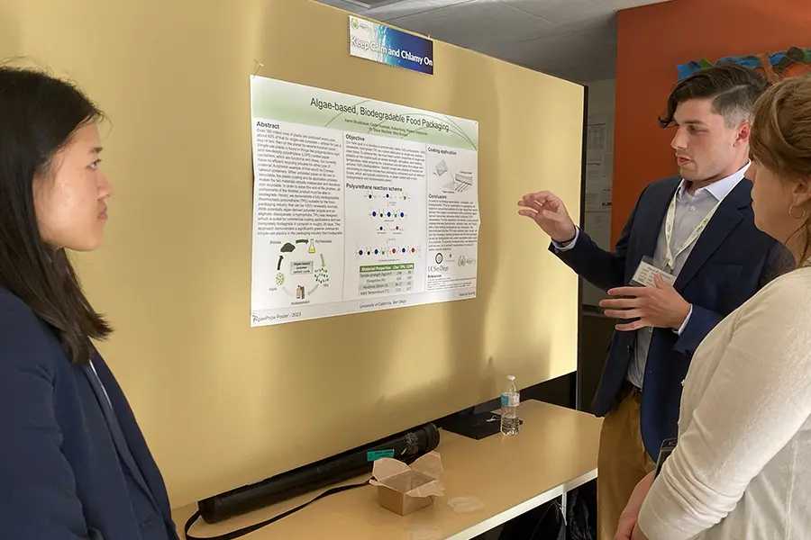 Person presenting a scientific poster on a board in an indoor setting.