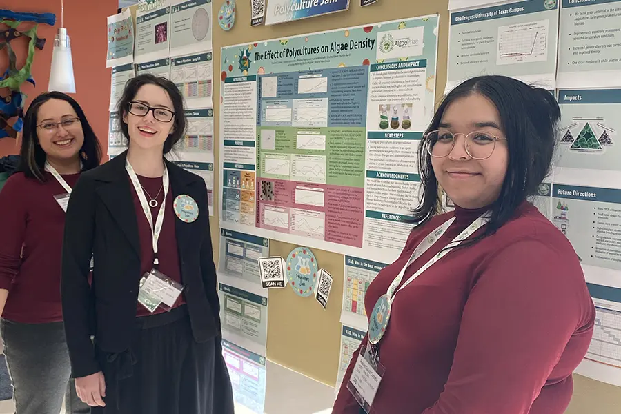 Two women standing in front of a detailed scientific poster presentation.