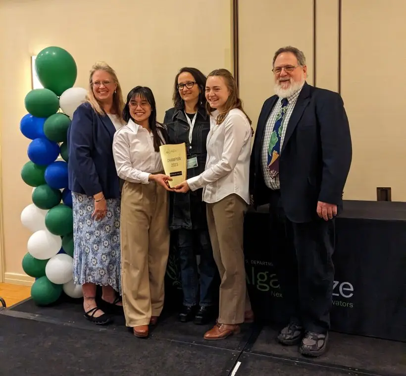 Five professionals holding an award, smiling at a ceremony.