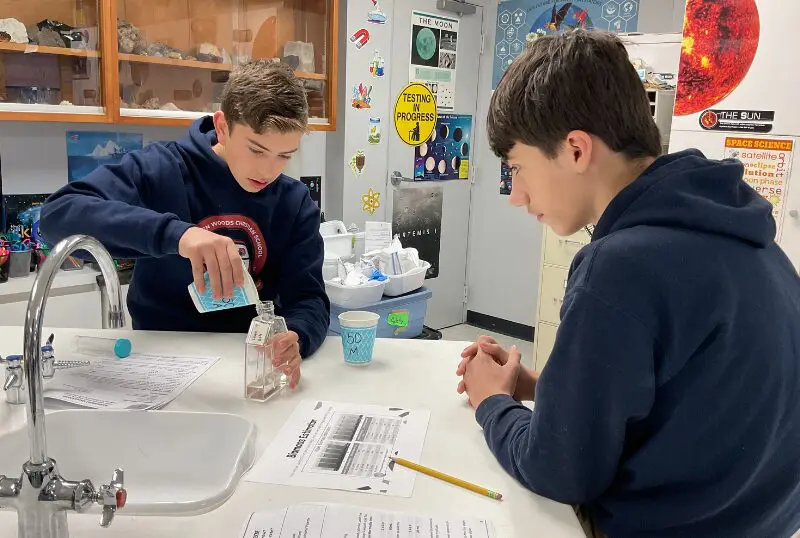 Two boys conducting a science experiment at a kitchen table.