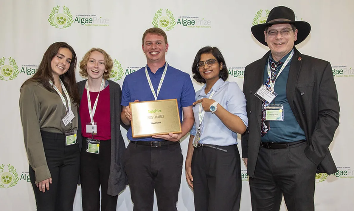 Four people posing at an event, one holding a plaque, all smiling.