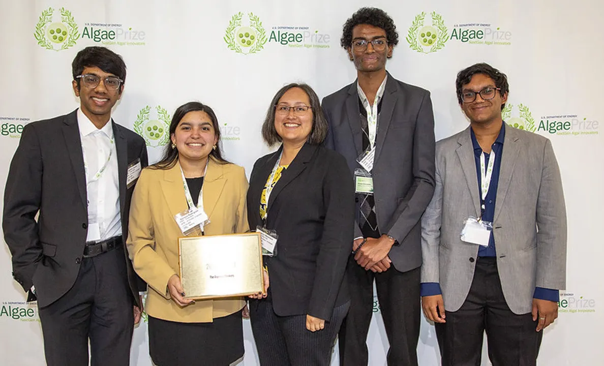 Four professionals posing with an award at an event.