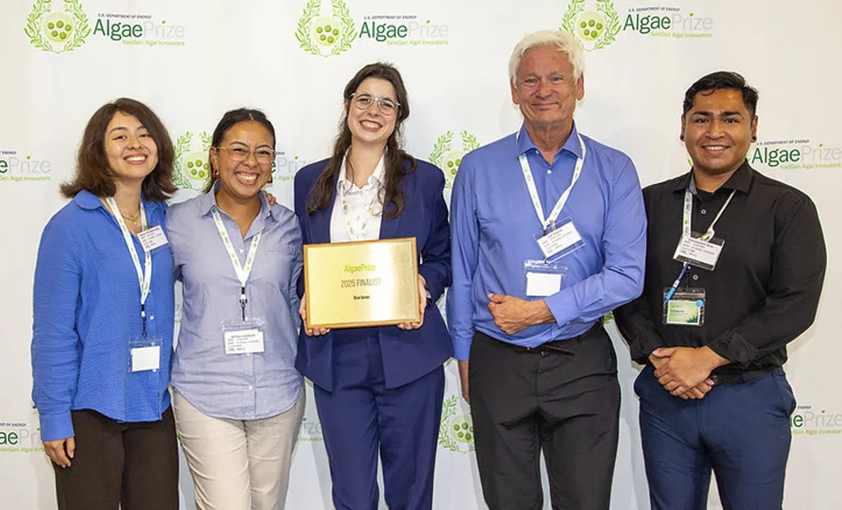 Four professionals posing with an award plaque at an event.