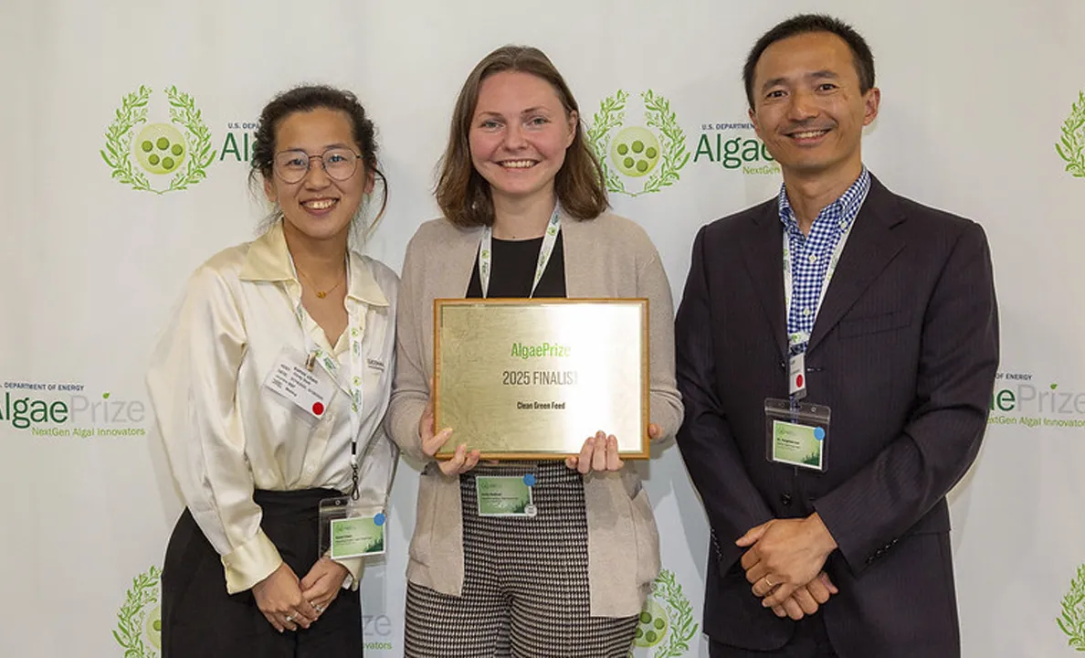 Three professionals pose with a certificate at a formal event.