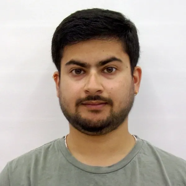 Portrait of a young man with short black hair and a trimmed beard wearing a grey t-shirt.