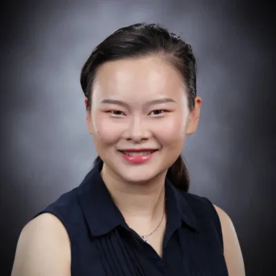 Professional headshot of a smiling woman with dark hair and a black sleeveless top.